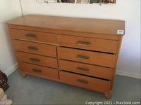View of vintage wood dresser with eight drawers, showing natural wood finish and signs of wear.