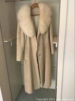 Full view of the vintage mohair coat with large white fur collar, button closure, and side pockets, hanging in closet.