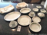 Full set of Noritake Diane china arranged on table showing plates, bowls, cups, saucers, serving platters and gravy boat, approximately 14 pieces total with one bowl missing.