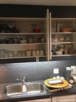 Kitchen shelves with crystal wine glasses, mugs, canisters, and trays displayed