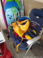 Photo showing Tommy Bahama folding chair with blue fabric, life vest(s), and parts of boogie boards behind