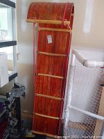 Front view of wooden toboggan leaning against wall showing length and construction