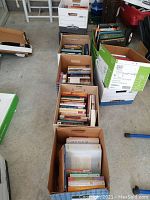 Six boxes of various religious books arranged on a floor, showing spines and covers in multiple boxes.