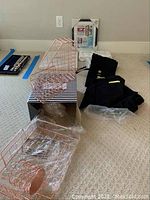 Rose gold wire mesh desktop organizer sets including magazine holder and smaller pieces placed on striped box, with folded black kimono and boxed items behind