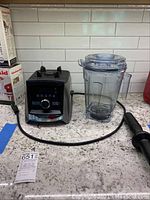 Blender base, pitcher, lid, tamper, and manual arranged on countertop