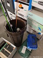Two hard plastic tackle boxes (one green, one blue) placed next to the fishing pole stand on the floor.