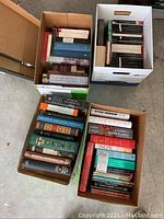Four boxes filled with assorted hard and soft cover books on history, philosophy, and biography