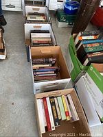 Four boxes filled with assorted books, visible titles include philosophy and self-help books in French and English.