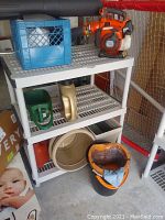 Overview of gas blower atop white plastic shelving with crate and shelf contents