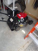 Full side view of mower with grass catcher attached on concrete floor