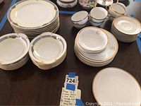 Photo showing multiple stacks of assorted dinner plates, salad plates, bowls, cups, and saucers on a table.