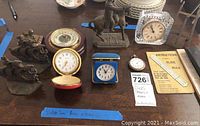 Overview of vintage clocks, bookends, figurine, slide rule with instructions, and porcelain dishes on a wooden table.
