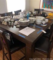 View of the dining table fully set with dishware, showing table surface and legs.
