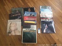 Photo showing a spread of multiple vinyl record album covers laid out on a hardwood floor. Albums include Miles Davis 'Sketches of Spain', Billie Holiday 'Lady in Satin', The Bobby Darin Story 'Mack The Knife', and others.