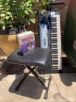 Full view of keyboard leaned against a wall, bench in front, and boxed Survival Kit on bench.