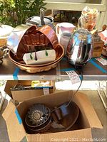 Wide view with copper jello molds, electric kettle, porcelain pitchers, and other kitchen pots and tins arranged on a surface.