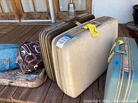Three large vintage Samsonite hard shell suitcases lying on floor alongside three assorted soft bags in background.