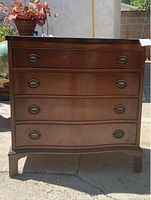 Front view of vintage dark wood dresser with four drawers and oval ring metal handles.