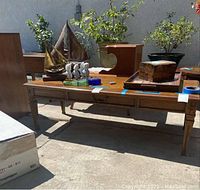 Front perspective view of the vintage wooden coffee table with a middle drawer, showing tapered legs and top surface with various decorative items (not included).