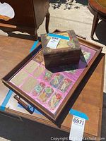 Wood tray holding a glass-covered display of antique Valentine's cards and a dark wooden decorative box with metal accents on top.