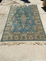 Full view of Ethan Allen area rug laid out on concrete, showing the full pattern and fringe.