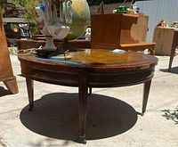 Photo showing full side view of round coffee table highlighting wooden legs and casters.