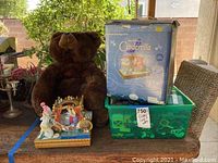 Disney Cinderella musical carriage figurine displayed in front of a large brown teddy bear, next to a green bin filled with LEGO pieces and the original Cinderella box.
