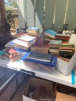 Overview image of assortment of books stacked on a table including vintage and antique books and some newer editions