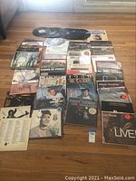 Overview of assorted vinyl records laid out on a wooden floor, showing album covers and some loose records.
