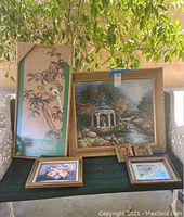 Six framed artworks displayed on a bench showing various bird and floral-themed paintings and prints.