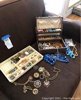 Overall lot on couch showing jewelry box, trays, necklaces and loose items