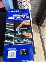 Box front showing Moen liquid soap and lotion dispenser branding and chrome finish image.