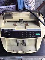 Frisco Bay bill counting machine showing keypad, display, feeding slot, and power cord.