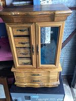 Front view of large wooden jewelry box showing glass doors and six drawers.