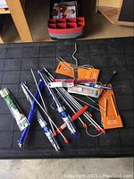 Overview of the lot showing mixed knitting needles and crochet hooks scattered on table, some still in original packaging.