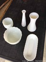 Top view showing all 5 milk glass items placed on a dark surface, including 3 bowls and 2 vases of varying sizes and textures.