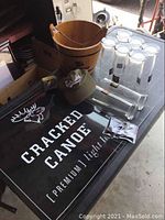 Photo of a wooden bucket, clear bar glasses, Cracked Canoe branded hat, two tall Cracked Canoe glasses, and an illuminated Cracked Canoe sign.