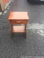 Front view of the wooden one drawer stand showing the drawer and lower shelf