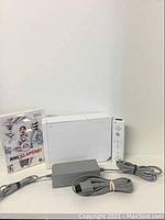 Full lot of Wii gaming console, controller, cables and game shown on a white background