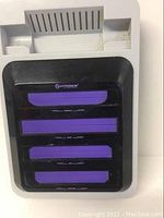 Top and front of the console showing the four cartridge slots for NES, SNES, Genesis, and Famicom games with purple inserts.