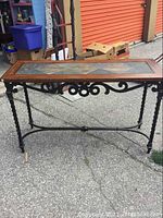 Full view of the hall table showing cast iron base with twisted legs and scrollwork supports and wooden frame with stone tile inset top.