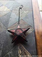 Side angle showing hanging chain, hook, and star's red patterned panels.