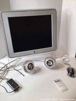 Front view of Apple adjustable monitor with connected spherical Apple speakers and wired mouse