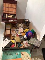 Photo showing five packs of playing cards, card shuffler, loose cards, game pieces, and parts of a Chinese Checker board