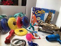 Photo showing dog toys including colorful frisbee-style discs, chew toys, a pink textured ball, a blue pet blow dryer, and the City Kitty cat toilet training kit box.