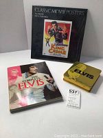 Photo showing the 2014 Classic Movie Posters calendar in unopened condition (cellophane opened but calendar unused), The Complete Elvis book, and a yellow Elvis tin holding the 3-CD set.