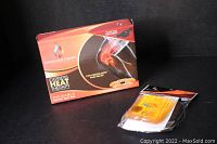 Heat pad box alongside brand new set of hand warmers in plastic packaging, heat pad visible through clear window on box.
