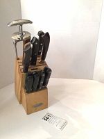 Farberware wooden knife block filled with knives and meat holder, displaying the front and top slots, showing various knife handles and meat holder handles.