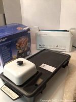 Image showing Weston non-stick flat grill with warming section and Oster food steamer in original box.