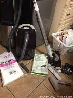 Kenmore canister vacuum with hose, power nozzle, several attachments, and vacuum bags on floor.